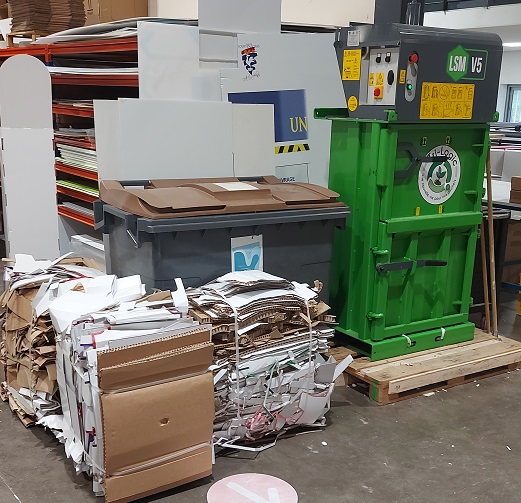 Presse à balle Tri-Logic utilisée pour compacter des cartons dans un atelier de fabrication de présentoirs en carton